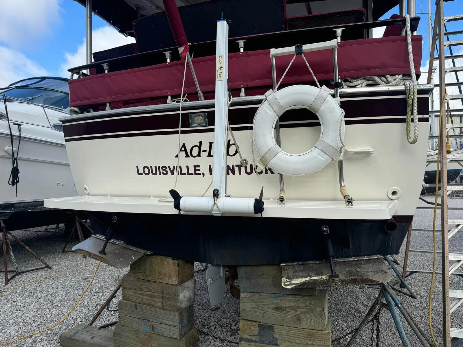 A boat on the hard with a DockStar unit strapped to a white vertical track on the transom, above the swim platform. The hull below it is unbroken: no through-hull fitting anywhere near the unit.