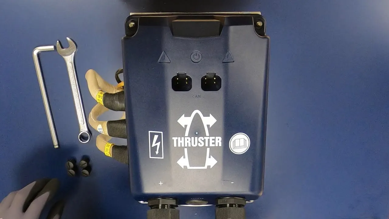 A still from VETUS's BOW PRO installation video: the thruster's dark blue controller from above, a wrench and hex key beside it and the motor cables plugged in.