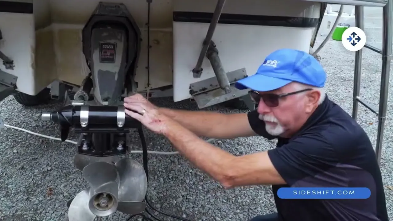 A still from Sideshift's installation video: a man in a blue cap installing the stern thruster to the sterndrive of a boat on its trailer.