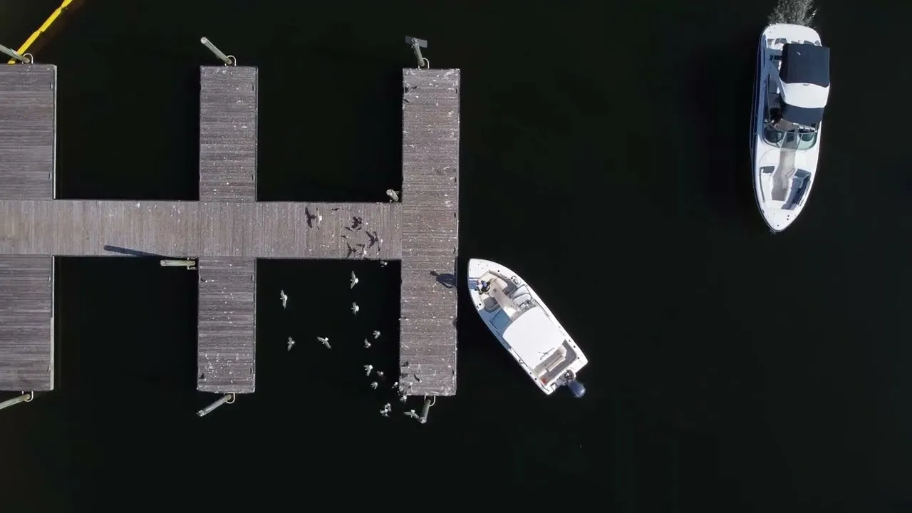 A still from Sideshift's docking video: a small runabout and a bowrider beside a dock, seen straight down from a drone.